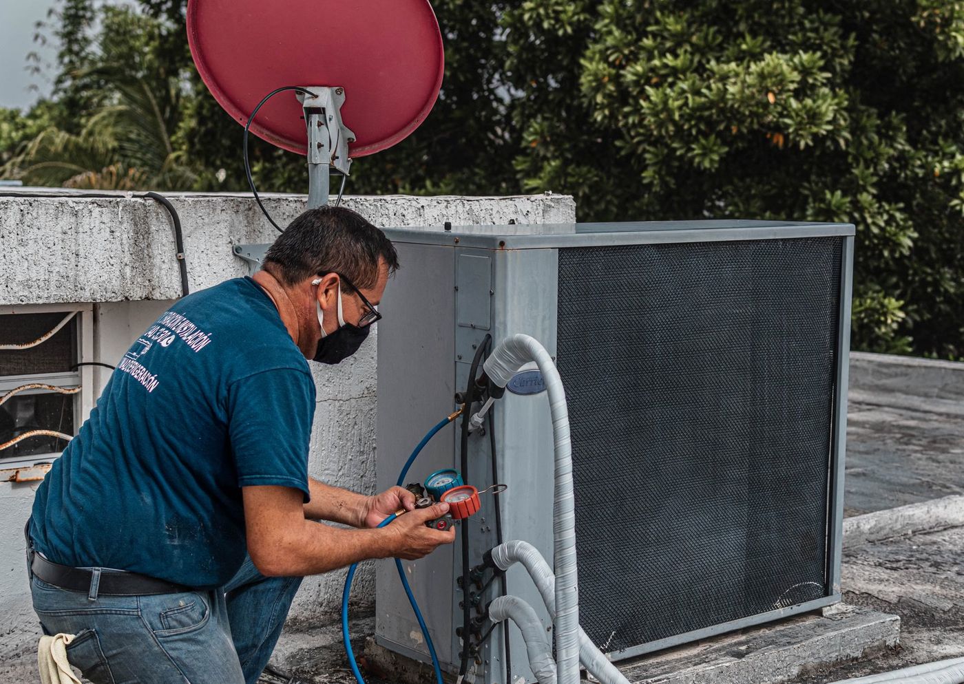 A technician servicing a home air-conditioning unit in daylight