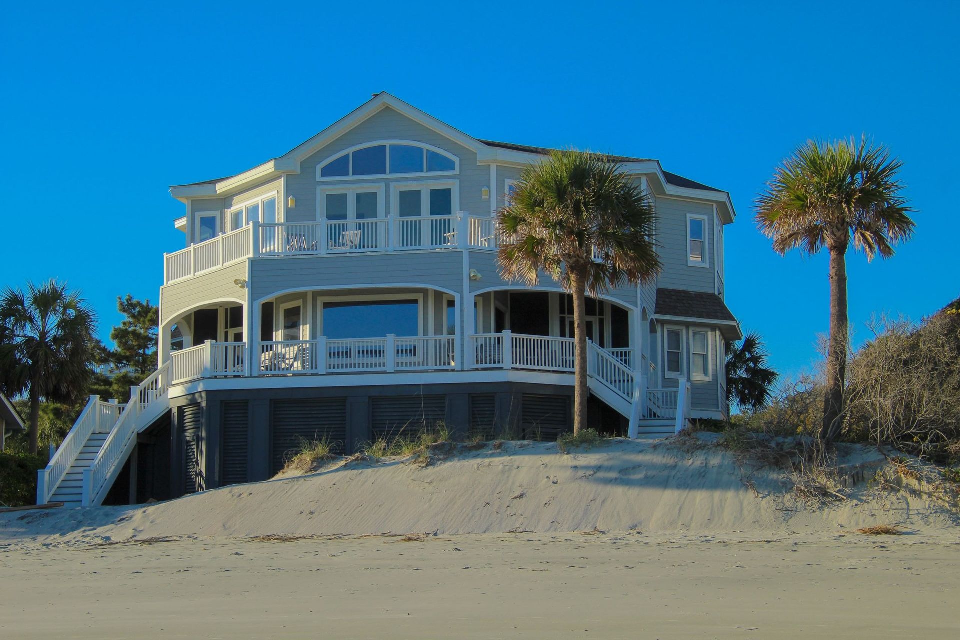 A bright coastal home with wraparound porches under a blue Texas sky