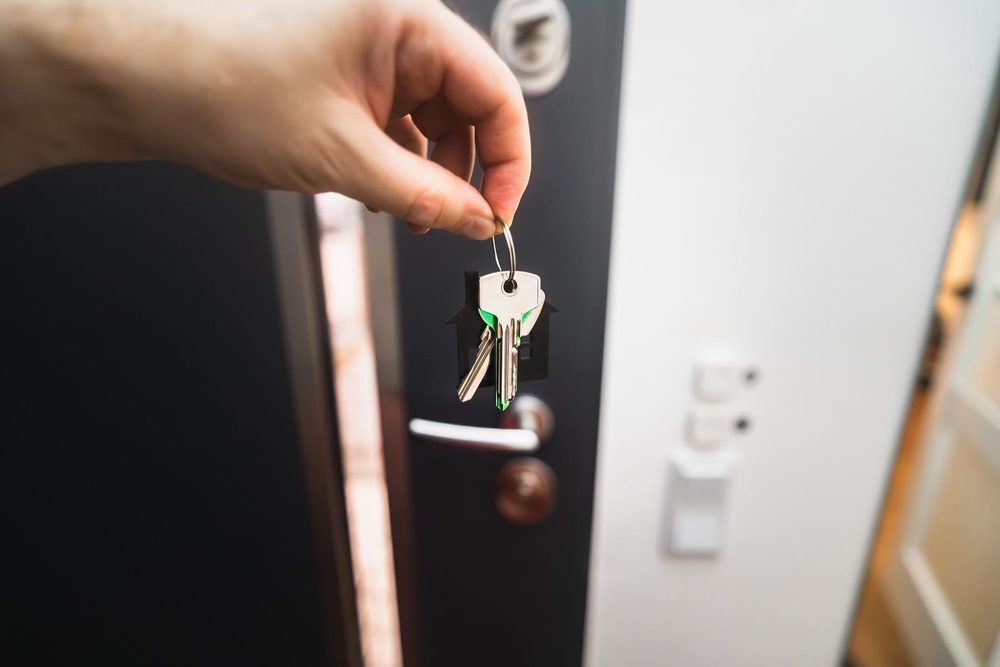 A hand holding the keys to a new home at its front door